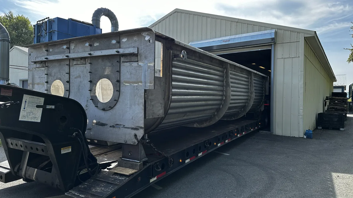 Paddle dryer trough arriving on a lowboy trailer at a drive-in door of the Longevity Coatings shop in Allentown